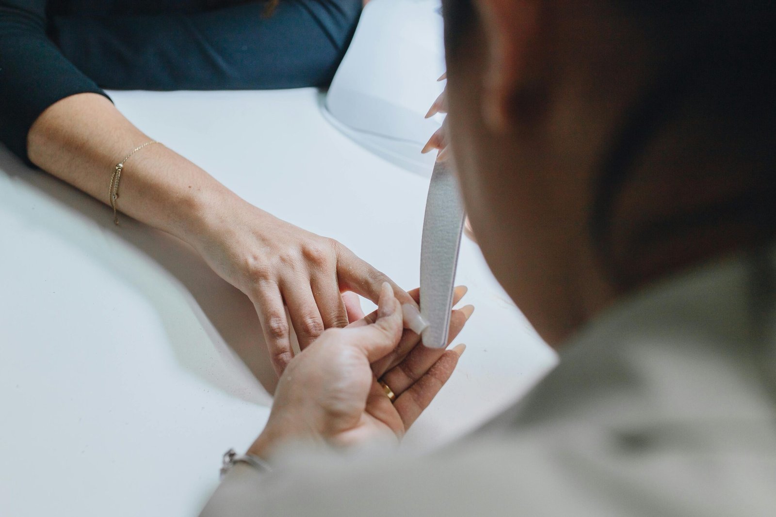Close-up of a manicurist filing nails during a professional manicure session in a salon.