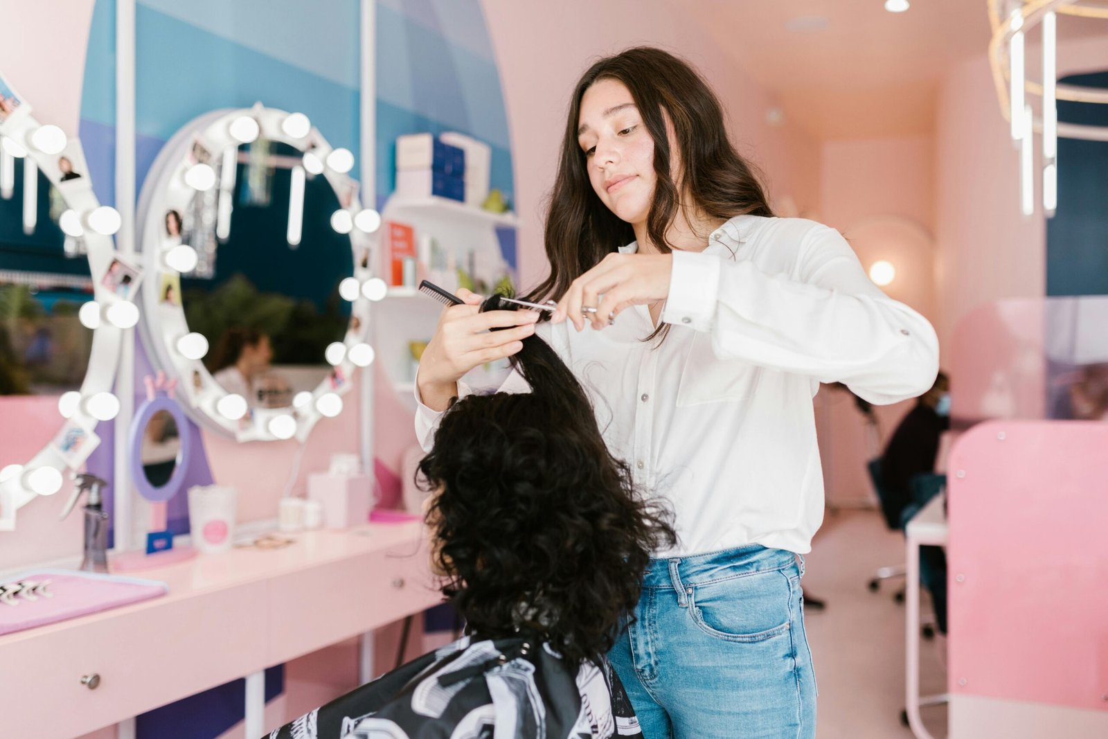 Hairdresser styling client's hair in a chic, modern salon with vibrant lighting.